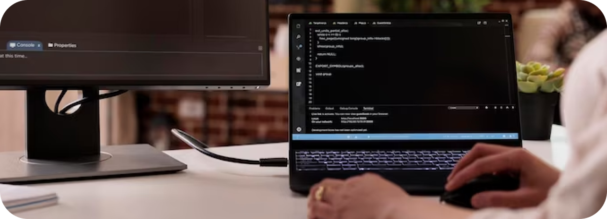 Se muestra una mesa con una computadora y una pantalla, mientras una persona las utiliza